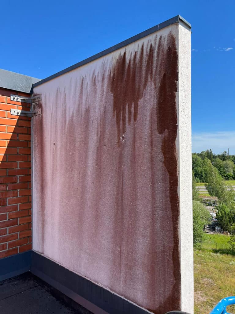 Punajäkälän värjäämä betoniseinä seinä ennen julkisivupesua.
